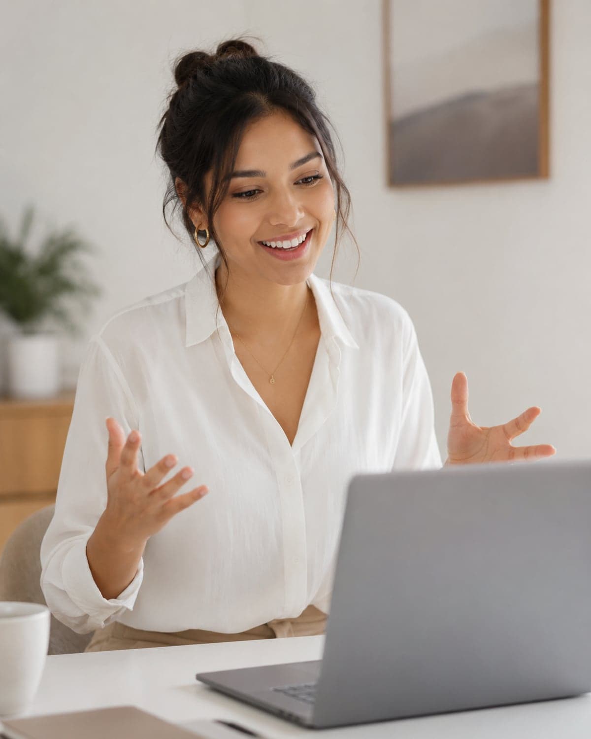A candidate smiling and gesturing while answering an interview question at her laptop